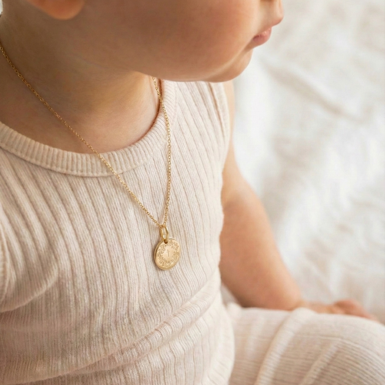 Christening medal featuring a wreath of flowers an