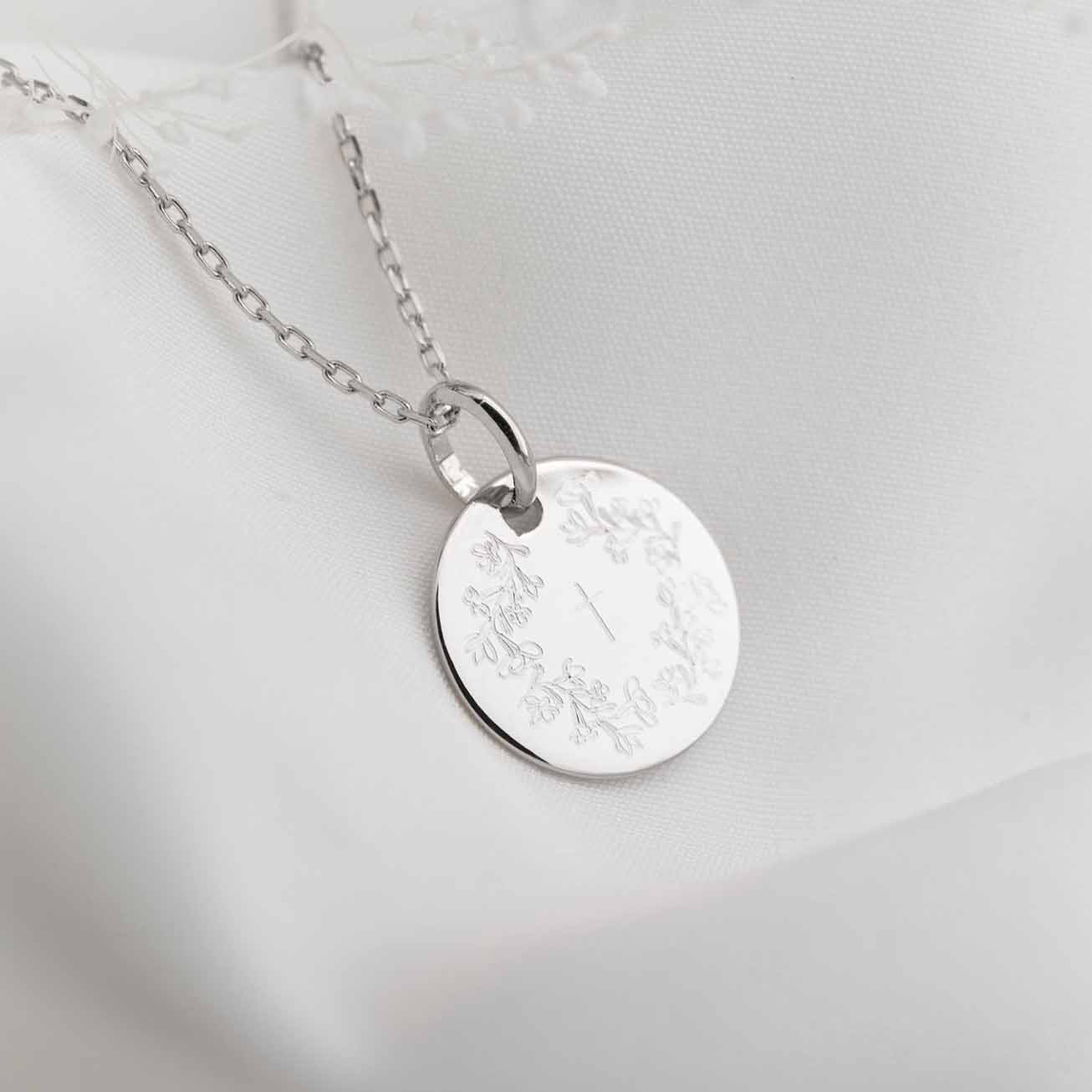 Silver baptismal medal with a wreath of flowers an